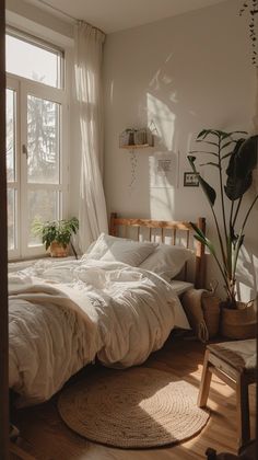 an unmade bed sitting next to a window in a room with wooden flooring