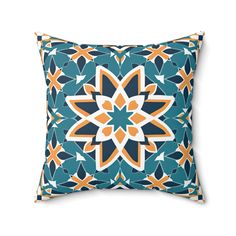 a blue and orange pillow with an intricate flower design on the front, sitting on a white background