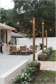 an outdoor patio with lights strung over it and seating area next to the bbq