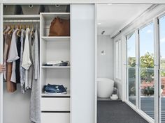 a person standing in front of a closet with clothes hanging on the rack and doors open