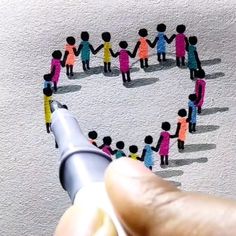 a hand holding a marker drawing a heart with small people