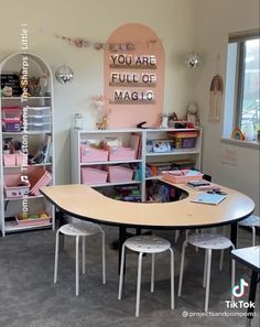 there is a table and chairs in the room with pink bins on the wall