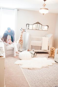 a man and woman sitting in a white room with a giraffe on the floor