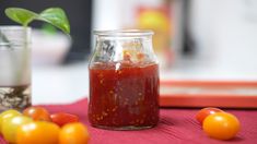 a jar filled with tomato sauce sitting on top of a table next to some tomatoes