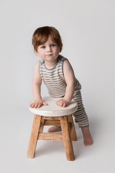 a baby sitting on top of a wooden stool