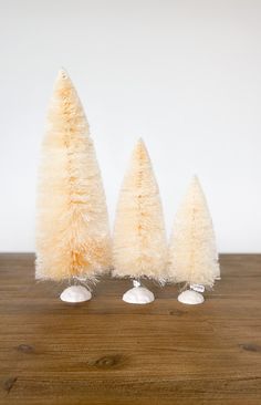 three small white trees sitting on top of a wooden table