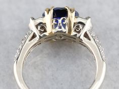 This sapphire is one of the finest gemstones currently found in our collection, and incredible fine gem that is filled with fire! The perfect shade of Cornflower, this gorgeous sapphire has flashes of violet and cobalt radiating from its center. Modern in manufacture, this opulent ring has a Renaissance feel, thanks to the European style split prongs, cast in lush yellow gold. The richness of these secure prongs creates a perfect contrasting frame for the sapphire at the center, while the perfectly balanced and immaculately set diamonds carry from the top of the ring all the way down the rounded shoulders. Metal: 18K Yellow and White Gold Gem: Sapphire 2.15 Carats Gem Measurements: 7.9 x 6.5 mm, Oval Accents: 2 Diamonds totaling .24 Carat, I in Color, SI2 in Clarity. 44 Diamonds totaling . Luxury Sapphire Gemstones With Multiple Stones, Luxury Sapphire Gemstones With Gemstone Accents, Luxury Sapphire Gemstones With Accent Stones, Luxury Trillion-cut Sapphire Ring, Luxury White Gold Sapphire Ring With Gemstone Accents, Fine Jewelry Polished Sapphire Ring, Luxury Trillion Cut Sapphire Ring With Center Stone, Luxury Sapphire Ring With Trillion Cut, Luxury Polished Lab-created Sapphire Ring