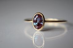 This lovely Lab-Created oval 6x4mm Alexandrite ring has a rich, romantic feel to it. I have set this 6x4mm stone into a solid 14k bezel cup. The 18 gauge band has been also highly polished for a very reflective shine to add to this sparkly stone. This style ring has an open back to allow light to pass through the stone. Material Information: Clarity: Occlusion free Color: Green, blue, purple Gemstone: Lab-Created oval 6x4mm Alexandrite  Metal: 14k yellow gold ★ IMPORTANT SHIPPING & PRODUCTION DE Oval Alexandrite Ring, Elegant Oval Ruby Ring For Proposal, Elegant Oval Bezel Set Birthstone Ring, Elegant Oval Sapphire Ring With Bezel Setting, Elegant Oval Ruby Ring With Bezel Setting, Oval Ruby Ring With Bezel Setting For Wedding, Oval Sapphire Ring In Yellow Gold For Proposal, Oval Bezel Set Engagement Ring, Stacked Rings Aesthetic