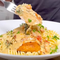 someone is taking a piece of chicken parmesan from a white plate with pasta