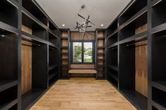 an empty walk - in closet with black shelves and wood flooring on the side