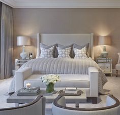 a large white bed sitting in a bedroom next to two tables with lamps on them