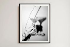 a black and white photo of someone holding a wine glass in front of a wall