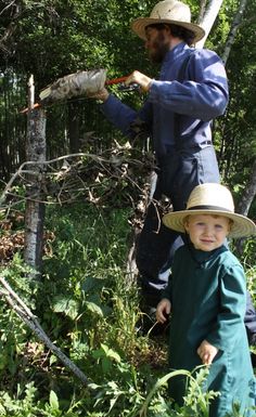 two people standing in the woods with hats on