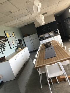 an empty kitchen with white chairs and wooden table in the center, next to a refrigerator