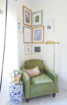 a green chair sitting in front of a window next to a blue and white vase