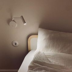 a white bed sitting next to a wall with a light on it's side