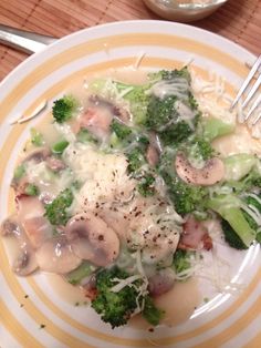 a white plate topped with broccoli covered in cheese and sauce next to a fork