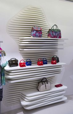 a white shelf with purses and handbags on it in front of a wall