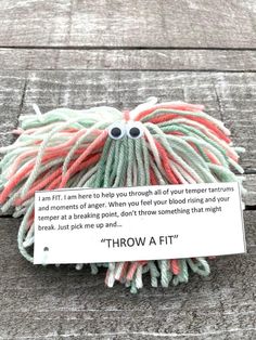 a ball of yarn sitting on top of a wooden floor next to a sign that says throw at it