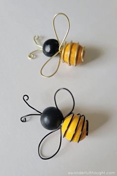 two wire sculptures made to look like bees and honeycombs on white surface