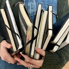 the person is holding several books in their hands and they both have binders attached to them