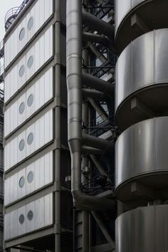 an industrial building with large metal pipes and round windows on the side, in front of a cloudy sky