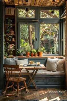 a table and chairs in front of a window with potted plants