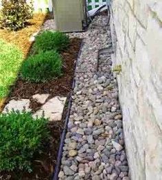 the side of a house with rocks and grass