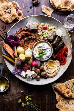 a plate full of different types of food on a table with crackers and bread