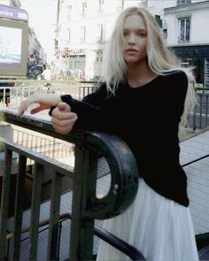 a woman leaning on a rail in front of a building