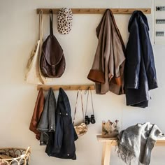 the coat rack is holding several coats and purses on it's hooks,