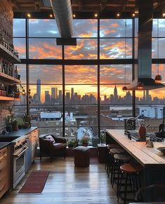 an open kitchen and living room area with large windows overlooking the cityscape at sunset