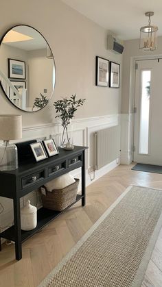 a living room with a black table, mirror and pictures on the wall above it