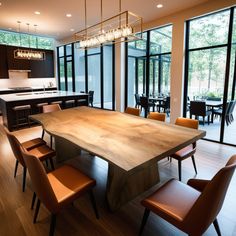 a large wooden table surrounded by chairs in a room with lots of windows and doors