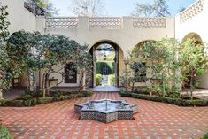 an outdoor courtyard with trees and bushes in the center, surrounded by red brick pavers