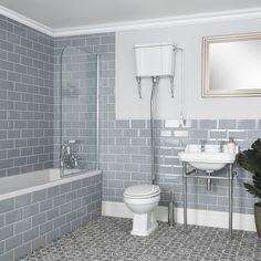 a white toilet sitting next to a bath tub under a window in a bathroom with blue tiles on the floor