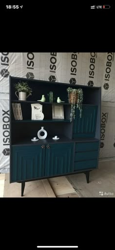 a black and blue cabinet with plants on it in front of a wallpapered background