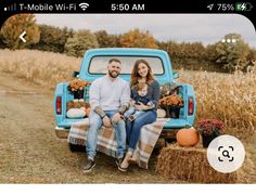 a man and woman sitting in the back of a blue truck with hay bales