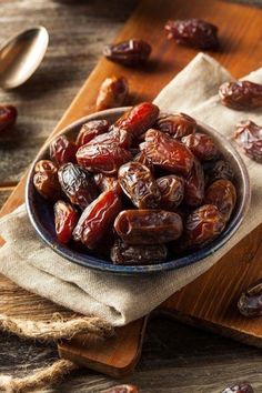 a bowl filled with dates sitting on top of a wooden table