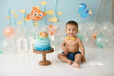 a baby sitting on the floor in front of a birthday cake with an ocean theme