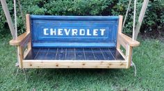 a wooden swing with the word chevrolet on it in front of some bushes and trees