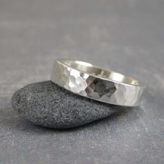 two silver rings sitting on top of a rock