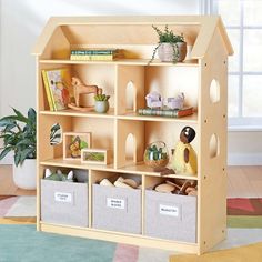 a wooden toy house shelf with toys and books