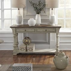 a wooden table with two vases on top of it next to a white wall