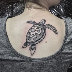 a woman's back shoulder with a turtle tattoo on it