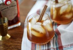 two glasses filled with iced drinks on top of a table