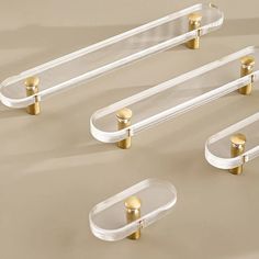 three clear and gold glass shelf brackets on a beige background