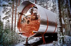 a large metal barrel sitting in the middle of a forest filled with lots of snow