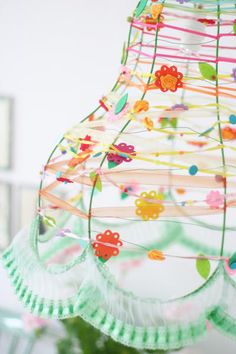 a colorful lamp hanging from the ceiling with paper flowers on it's lampshade