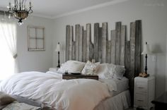 a bed with white linens and pillows in a bedroom next to a wall made out of wooden planks